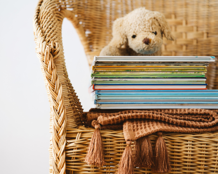 A stack of books with a stuff puppy sitting on a wicker chair.