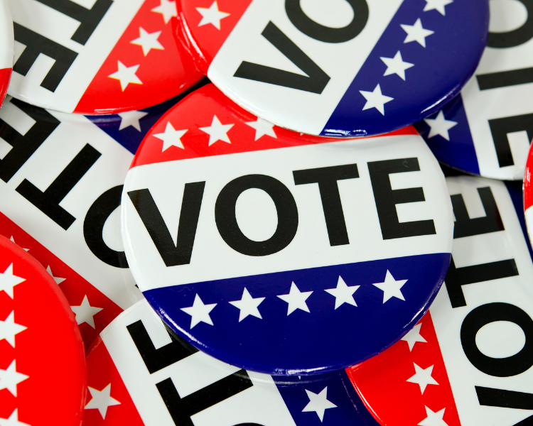 Various voter buttons with the word VOTE and red, white, and blue design.