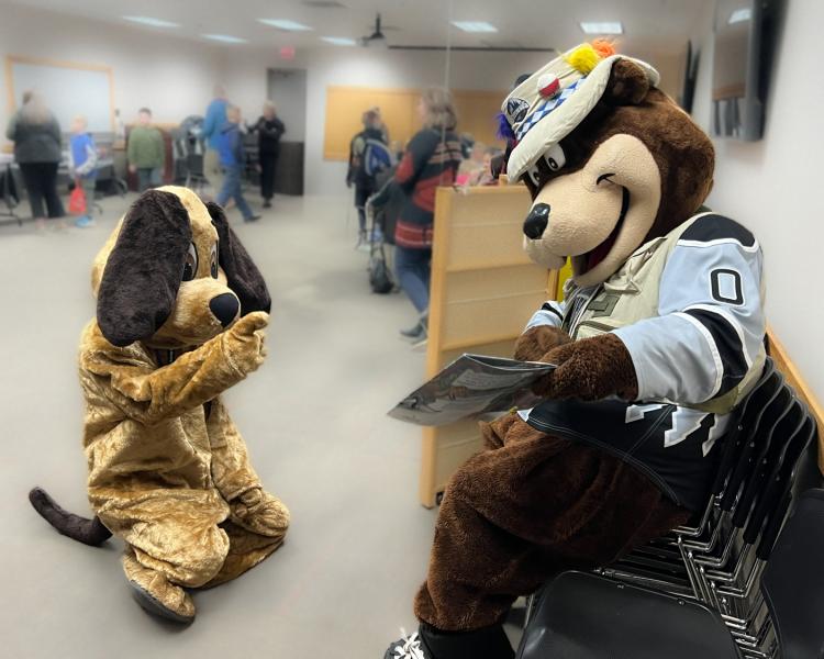 Mascots Rascal and Blue reading a book